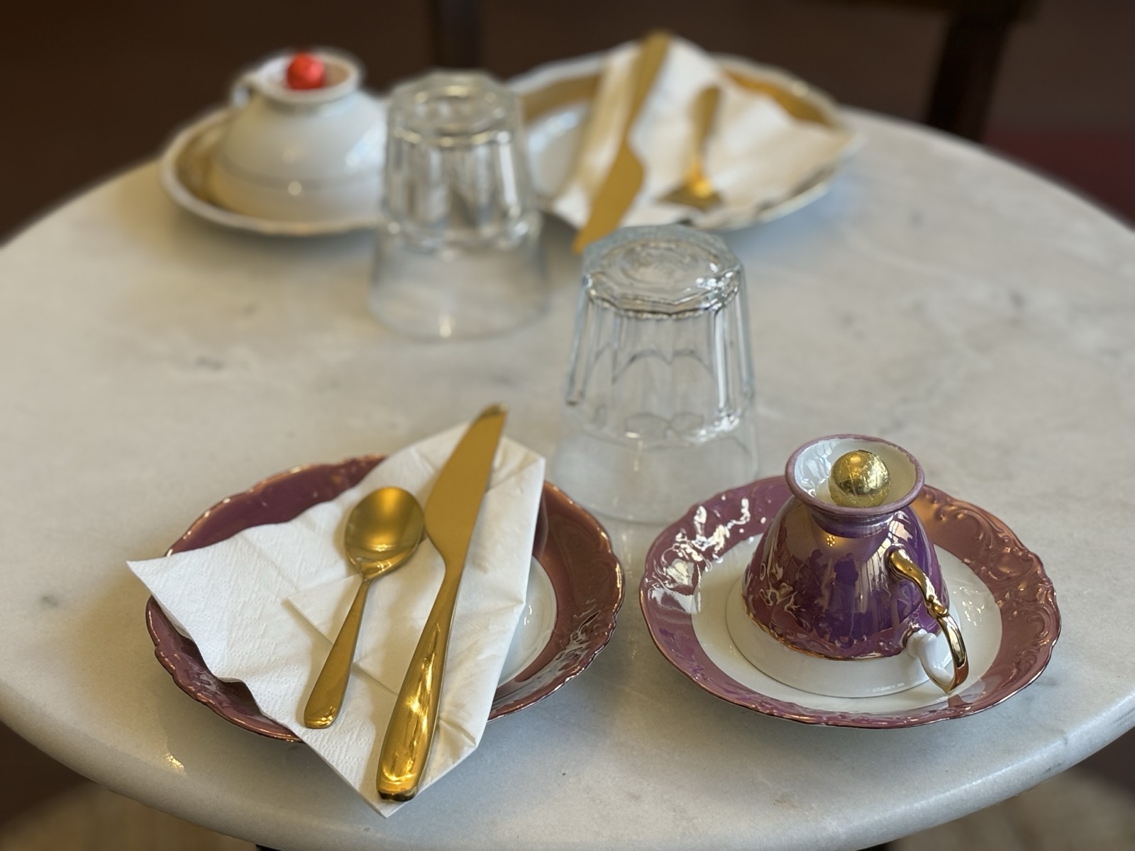 Gedeckter Tisch mit rosa Tasse und goldenem Besteck